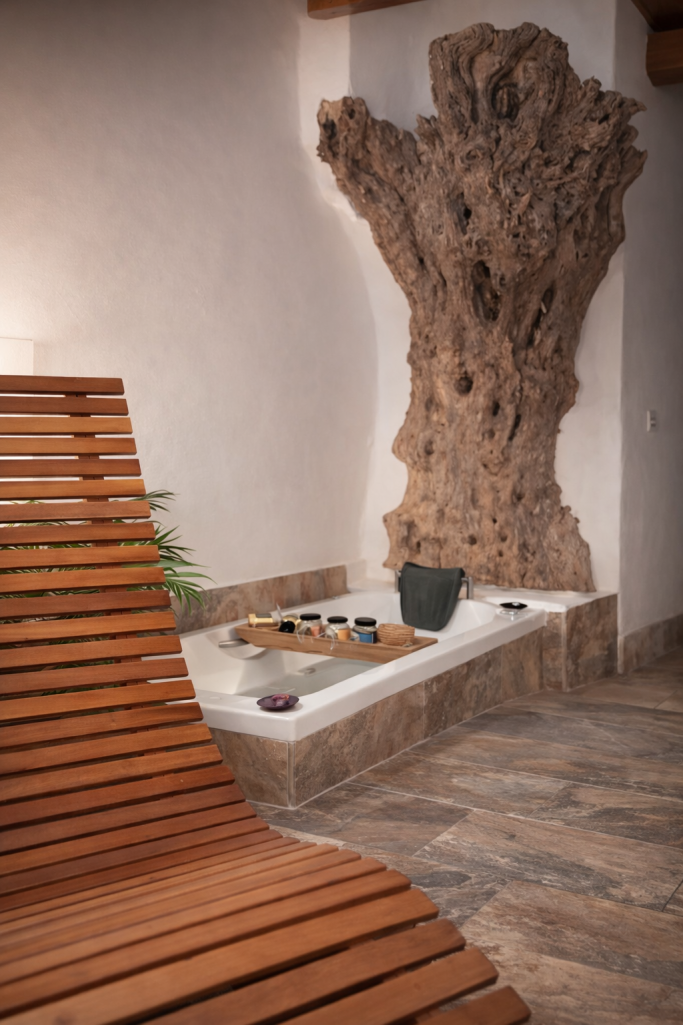 Silla de madera junto a pared de corteza y mesa con utensilios en un ambiente relajante.