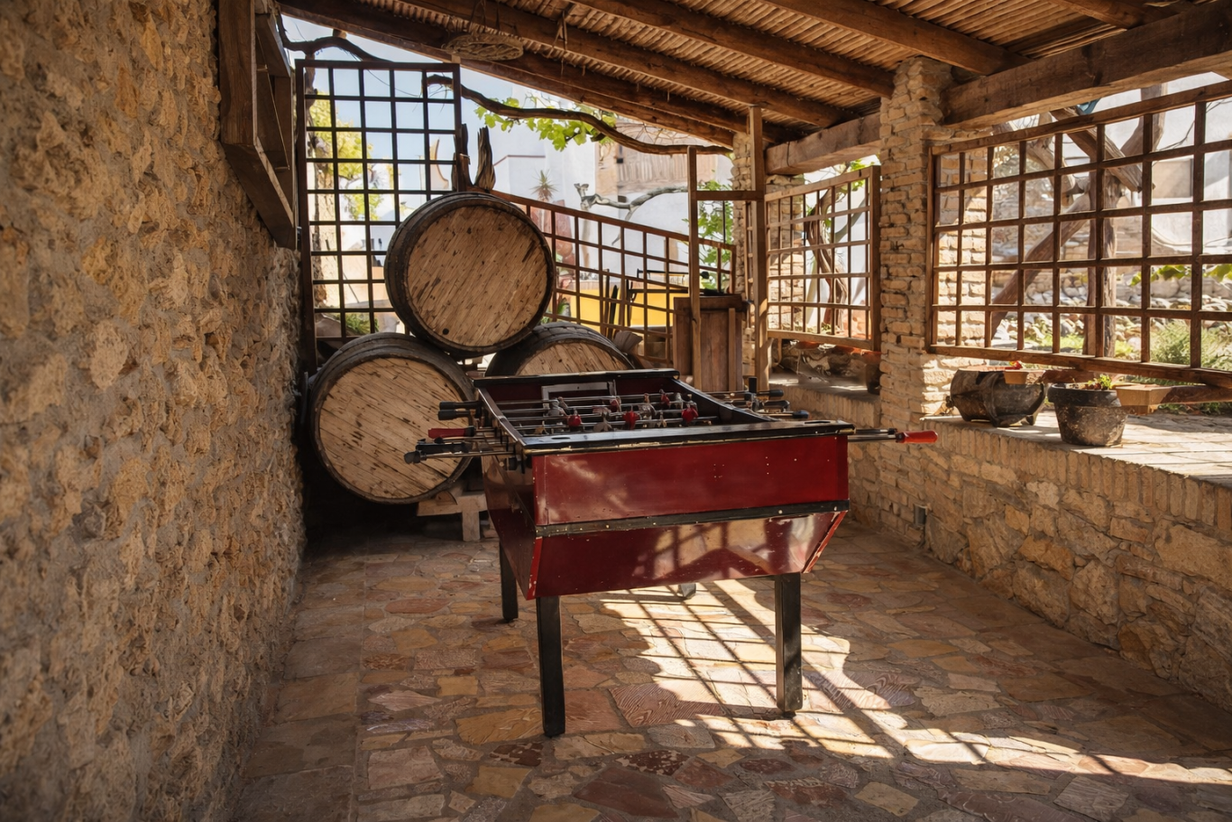 Una sala rústica con un horno rojo, barricas de madera y paredes de piedra.