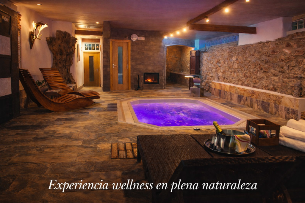 Spa acogedor con piscina iluminada y ambiente de piedra natural. Toallas y sillas disponibles.