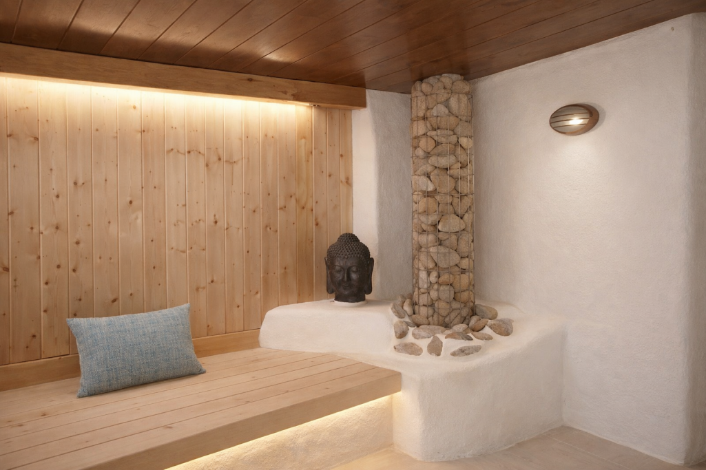 Interior de un spa con piedra, madera y luz cálida, ofreciendo un ambiente relajante.