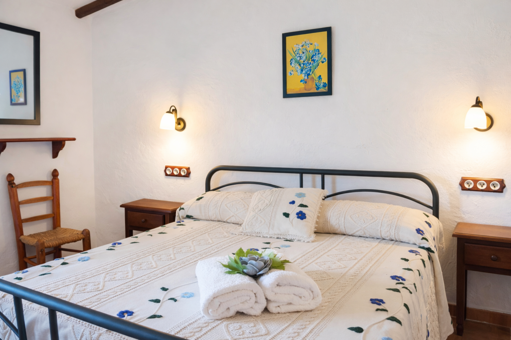 Habitación con cama doble, decoración sencilla y toques de color en paredes y textiles.